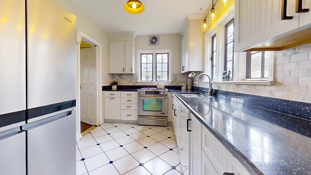 kitchen with decorative backsplash, sink, white cabinets, stainless steel stove, and fridge