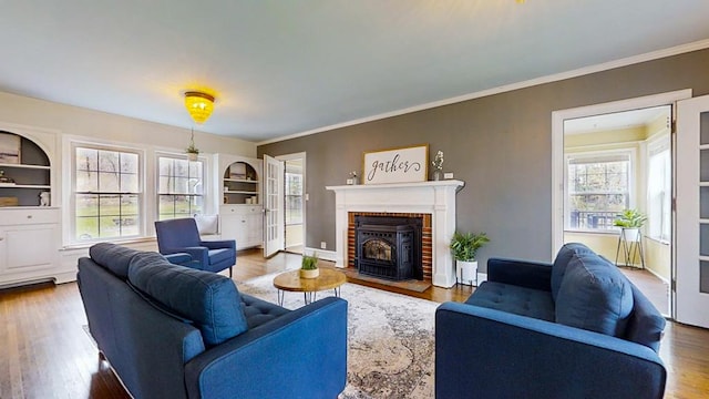 living room with hardwood / wood-style floors, a wood stove, plenty of natural light, and crown molding