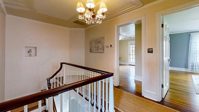 hallway featuring an inviting chandelier, ornamental molding, and hardwood / wood-style flooring