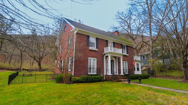 colonial house with a balcony and a front lawn