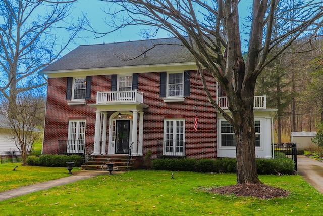 colonial home with a front yard and a balcony