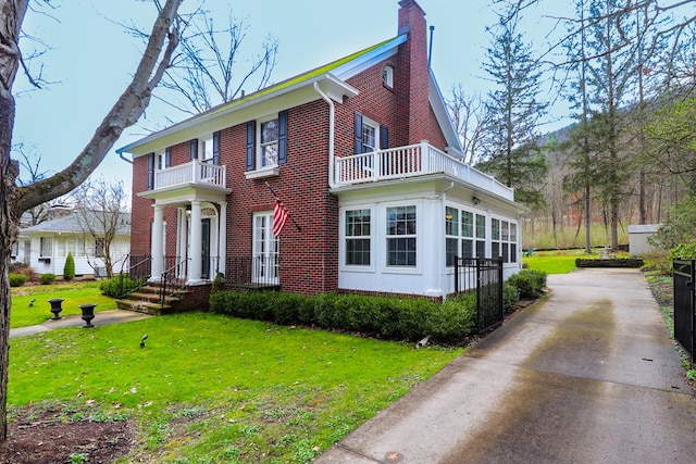 view of front of house featuring a balcony and a front lawn