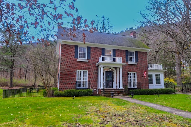 colonial-style house with a front yard and a balcony