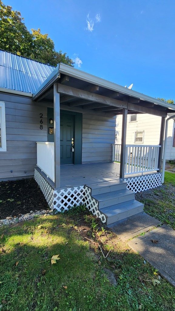 entrance to property featuring a lawn and a porch