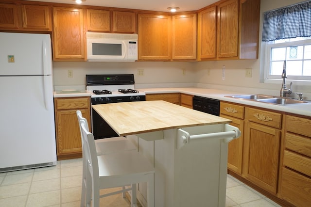 kitchen featuring white appliances, sink, a kitchen island, wooden counters, and a breakfast bar