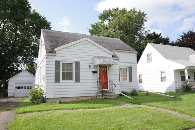 view of front of home with a garage, a front lawn, and an outbuilding