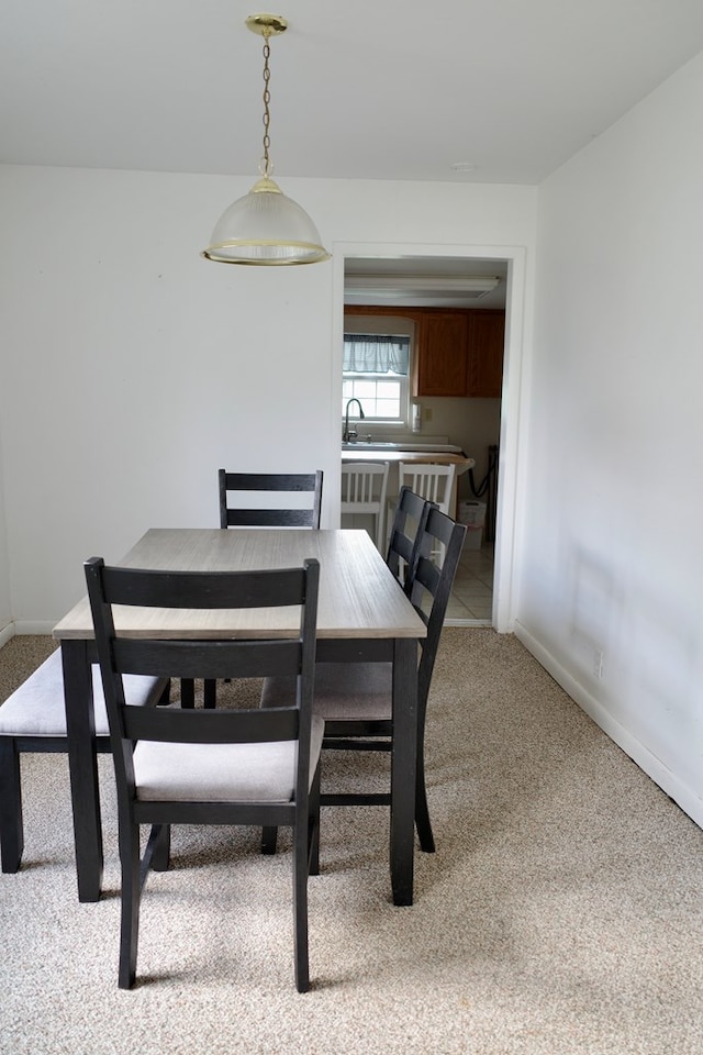 dining space with sink and light colored carpet