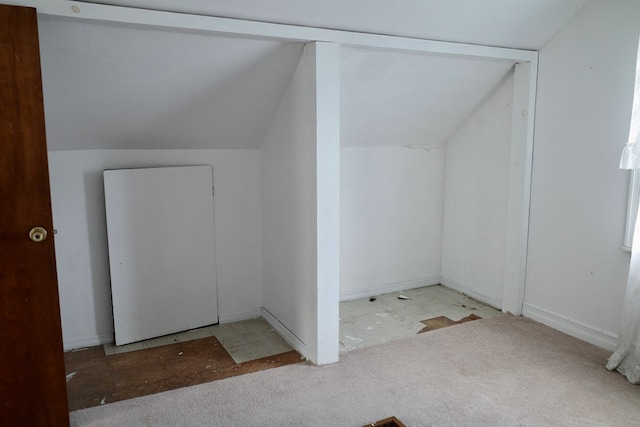 additional living space featuring vaulted ceiling and light colored carpet