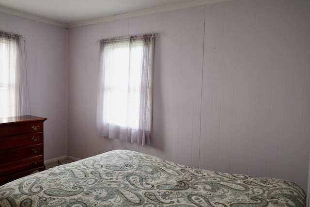 bedroom featuring ornamental molding, multiple windows, and wood walls