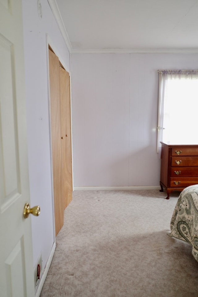 bedroom with ornamental molding, wooden walls, light colored carpet, and a closet