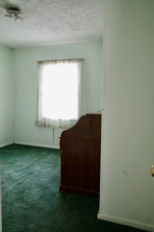 empty room with a textured ceiling and dark carpet