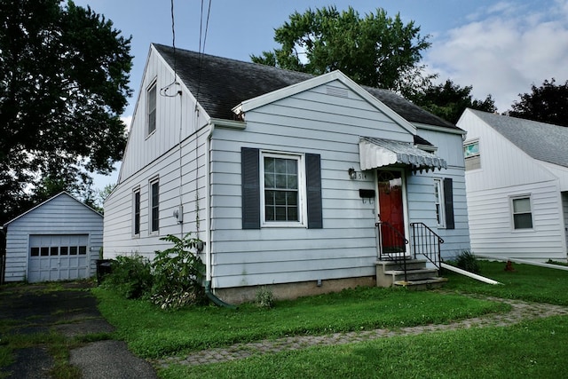 view of front of house with a front yard, a garage, and an outdoor structure