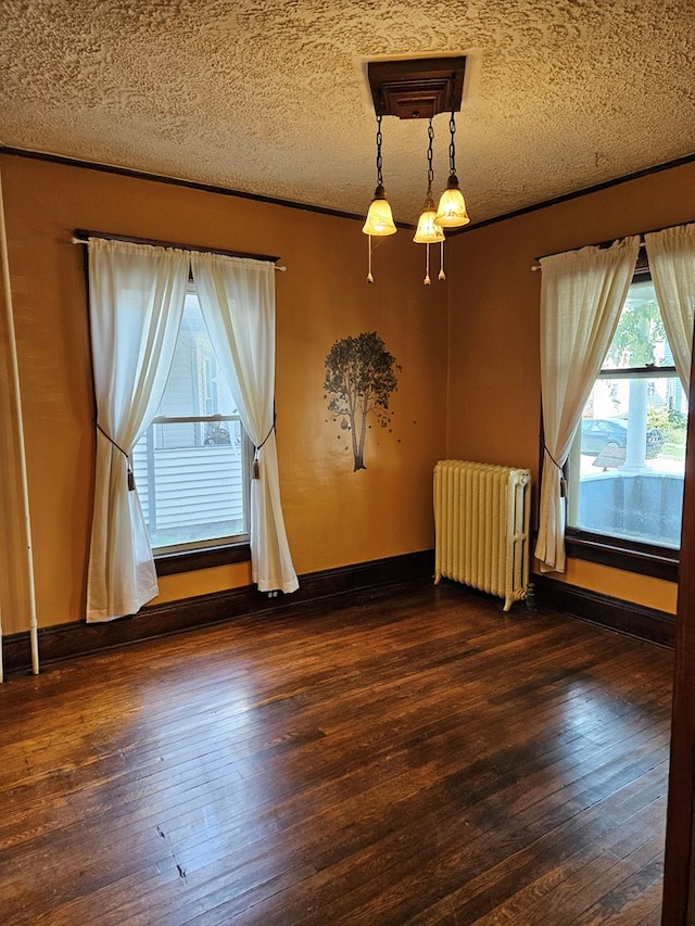 unfurnished room featuring dark wood-type flooring, radiator, and a textured ceiling