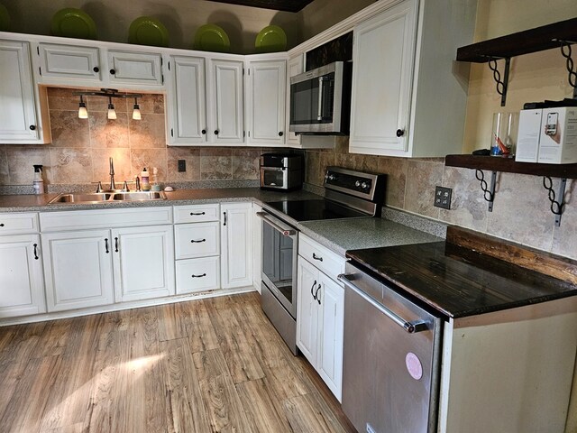 kitchen featuring decorative backsplash, light hardwood / wood-style flooring, sink, white cabinetry, and appliances with stainless steel finishes