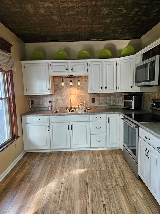 kitchen with appliances with stainless steel finishes, white cabinets, and sink