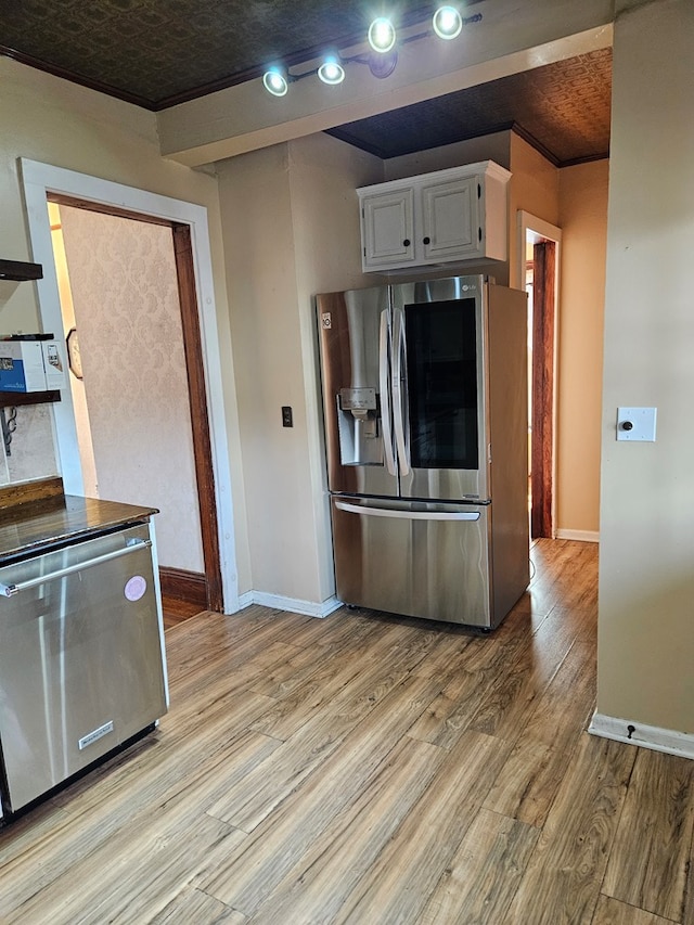 kitchen with stainless steel appliances, white cabinetry, and light wood-type flooring