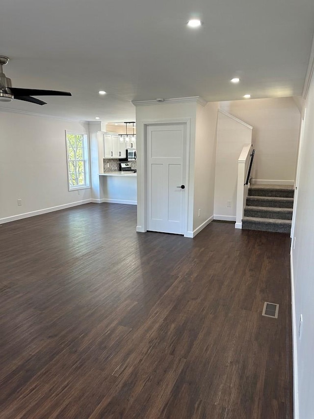 unfurnished living room with crown molding, ceiling fan, and dark hardwood / wood-style floors