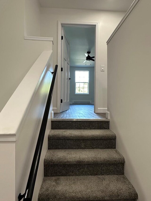 staircase with ceiling fan and a baseboard heating unit