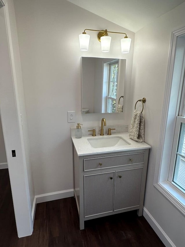 bathroom featuring vanity, hardwood / wood-style flooring, vaulted ceiling, and a wealth of natural light