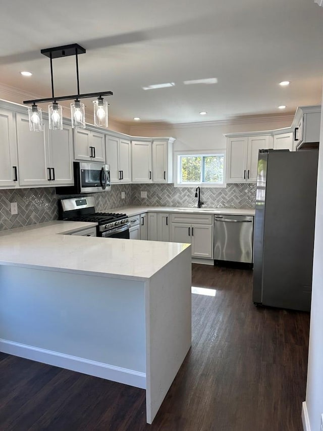 kitchen with kitchen peninsula, dark hardwood / wood-style floors, stainless steel appliances, and decorative light fixtures