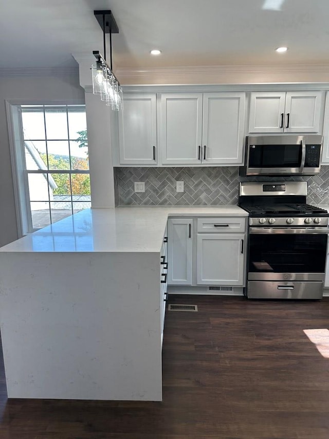 kitchen featuring white cabinets, decorative light fixtures, dark wood-type flooring, and appliances with stainless steel finishes