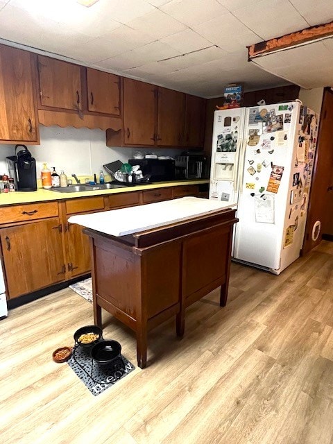 kitchen featuring white fridge with ice dispenser, light hardwood / wood-style flooring, and sink