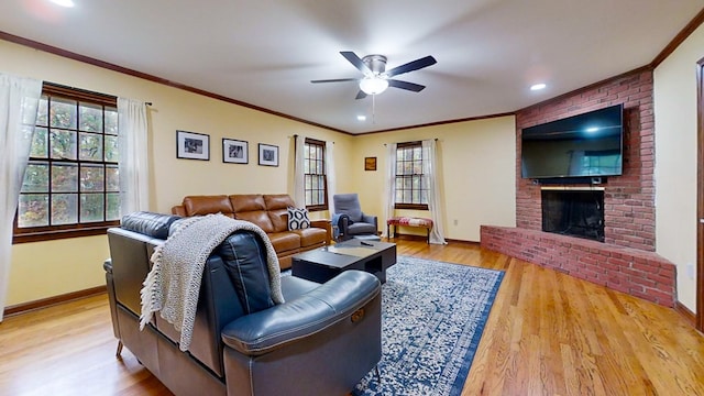 living room with ceiling fan, a fireplace, a healthy amount of sunlight, and light wood-type flooring