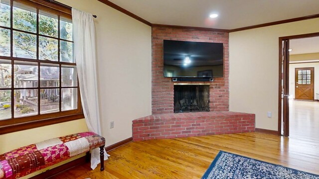 living room featuring hardwood / wood-style flooring, ornamental molding, and a brick fireplace