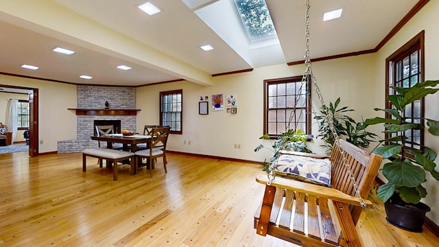 dining area featuring light wood-type flooring, ornamental molding, and a brick fireplace