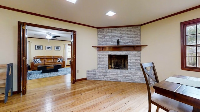 living room featuring crown molding, a fireplace, ceiling fan, and light hardwood / wood-style floors