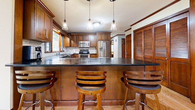 kitchen featuring backsplash, light hardwood / wood-style floors, stainless steel appliances, and a breakfast bar area