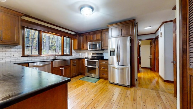 kitchen with decorative backsplash, crown molding, appliances with stainless steel finishes, and light hardwood / wood-style flooring