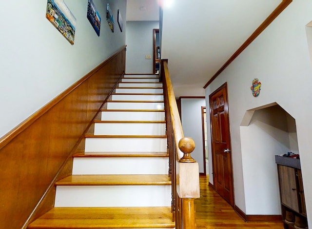 staircase featuring crown molding and wood-type flooring