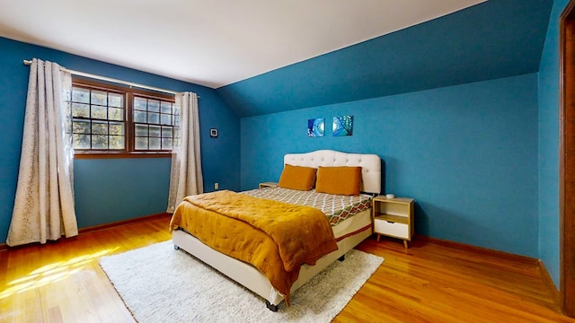 bedroom with hardwood / wood-style flooring and lofted ceiling