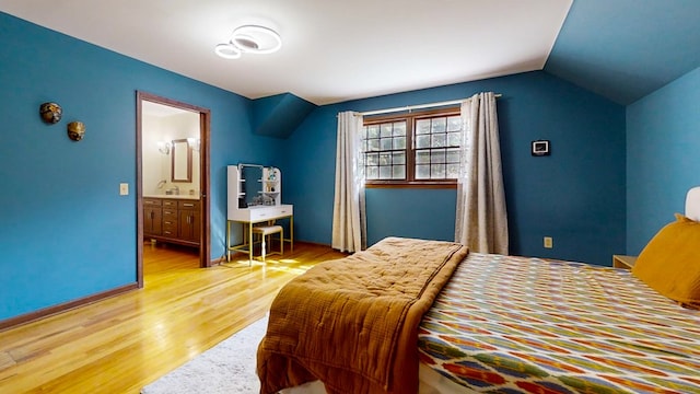 bedroom featuring ensuite bathroom, vaulted ceiling, and light hardwood / wood-style flooring