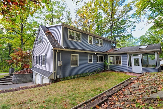 rear view of house featuring a sunroom, a yard, and a garage