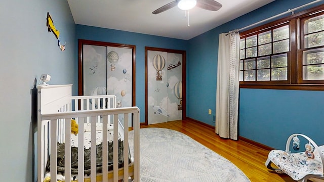 bedroom featuring hardwood / wood-style flooring, ceiling fan, and a crib