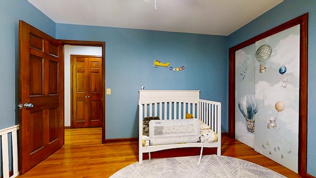 bedroom with a crib and light hardwood / wood-style floors