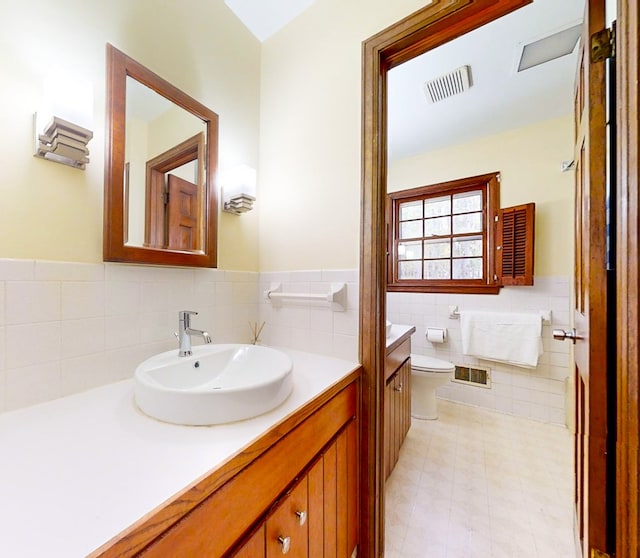 bathroom with vanity, toilet, and tile walls