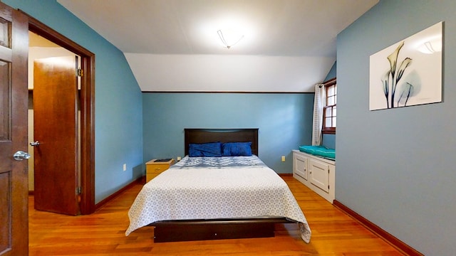 bedroom with vaulted ceiling and light wood-type flooring