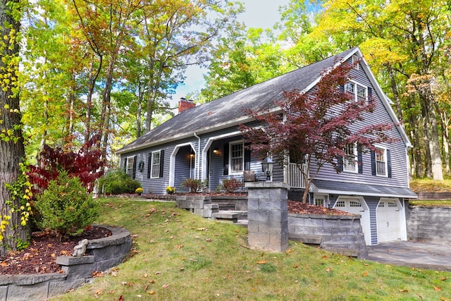 view of front of property featuring covered porch, a garage, and a front lawn