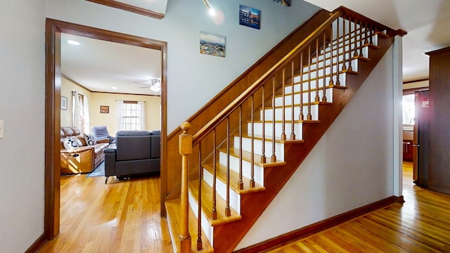 staircase with ceiling fan, wood-type flooring, and ornamental molding