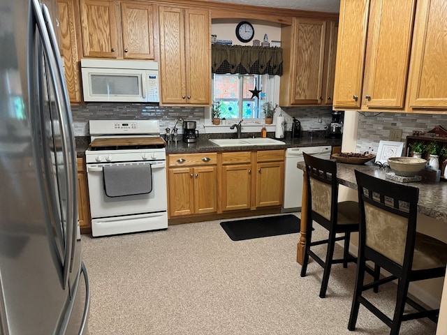 kitchen featuring white appliances, a breakfast bar, sink, and decorative backsplash