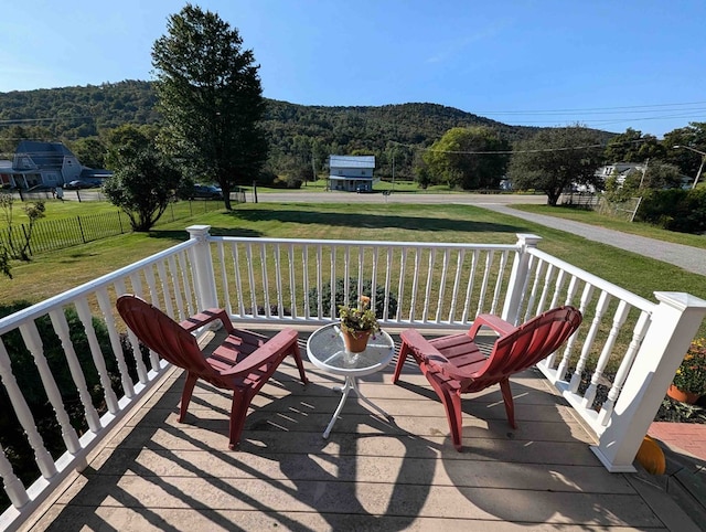 wooden terrace featuring a mountain view and a lawn