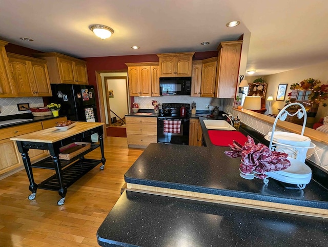 kitchen with light wood-type flooring, sink, tasteful backsplash, and black appliances