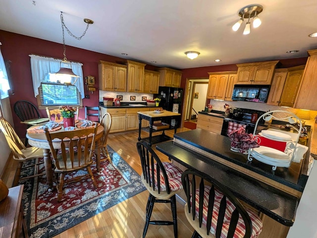 kitchen featuring pendant lighting, light hardwood / wood-style floors, black appliances, and sink