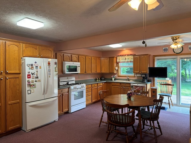 kitchen with a textured ceiling, dark colored carpet, ceiling fan, and white appliances