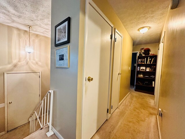 corridor with light colored carpet and a textured ceiling