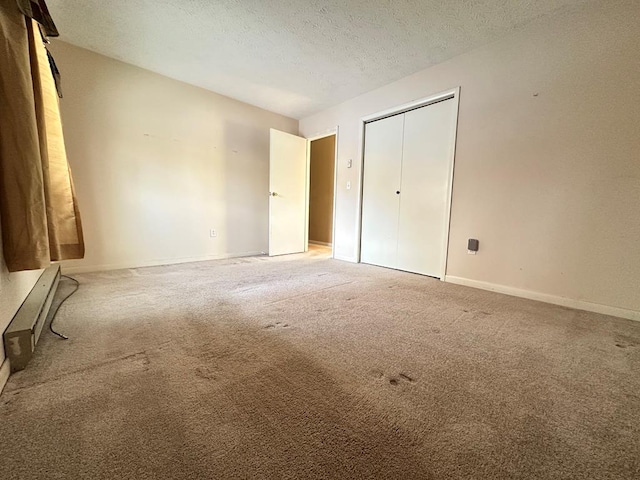 unfurnished bedroom with a textured ceiling, carpet floors, a baseboard radiator, and a closet