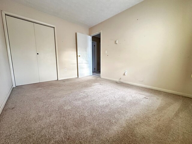 unfurnished bedroom with a closet, carpet floors, and a textured ceiling